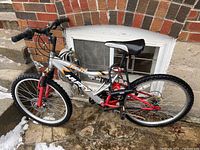 Side view of the Tundra-Huffy 18 speed bicycle with silver and red frame, black and white saddle, front and rear wheels 24 inches with tires, showing general condition and design.