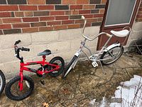 Photo showing two bicycles side by side against a brick and concrete wall, Schwinn Chick on right and Spark-Avigo smaller bike on left.