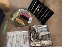 Overview of bracelets on trays and display board showing assortment of metal, beaded, and rhinestone bracelets in various colors and styles.