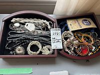 Overview of two wooden drawers filled with assorted costume jewelry including necklaces and bracelets with tags visible