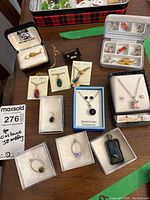 Full spread of costume jewellery including necklaces, earrings, pendants, and box containers with various charms and accessories.