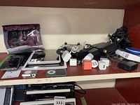 Photo of shelf with multiple Apple devices including iPads, iPods, iPhone, charging adapters, cables, and accessories scattered