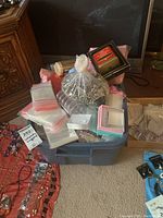Bin containing assorted jewelry packaging supplies and loose jewelry components including beads, boxes, cords, and bags