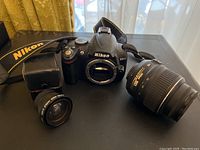 Nikon D300 body on table with kit zoom lens at right and wide converter at left