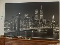 Full view of the large black and white Chicago cityscape canvas print resting on furniture, showing the size relative to the surrounding room elements.
