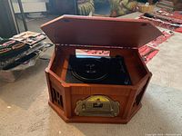 Hexagonal wooden console radio with lid open showing turntable on top and gold-tone radio tuner on front.