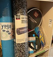 Photo showing blue new yoga mat, Everlast foam roller in original packaging, Wilson tennis racket, Copper Fit elbow brace, and mouthguards packaged.