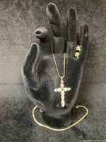 Black-hand display showing S chain, filigree cross pendant and crucifix earrings