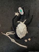 Photo showing the five piece jewelry set displayed on a black stand including leaf pendant necklace, bracelet, star brooch, flower earrings, and silver filigree brooch.