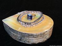 Set of two tennis bracelets and cocktail ring placed on top of the large shell jewelry box showing overall items in the lot.