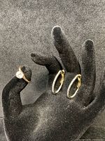 Ring worn on finger with earrings displayed on mannequin hand