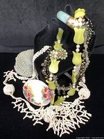 Overview showing jade bangle, two necklaces, brooch, earrings and beaded coin purse