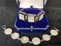 Both bracelets displayed on black surface inside blue jewelry box