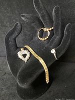 Photo of all four jewelry pieces displayed on black hand stand including the heart pendant, bracelet, ring, and earrings.