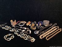 Full view of all jewelry pieces including watches, bracelets, and necklaces laid on black background showing metal and resin materials and wear.