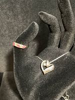 Image showing antique ruby and diamond ring on display stand alongside silver chain with heart pendant.