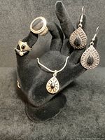 Display of all six jewelry pieces on black velvet hand stand, showing large teardrop marcasite and black onyx earrings, two small sterling silver and onyx rings, a larger unmarked ladies ring with onyx, and the serpentine chain necklace with teardrop pendant.