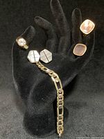 Overall display on black glove showing all pieces: pinkie ring with clear stone, Figaro bracelet, mother of pearl and abalone cuff links.