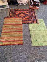 All three rugs and bath mat laid on the floor, showing size and color differences.