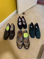 Four pairs of ladies' size 8 shoes on carpet near a yellow wall and door, showing front and side views.