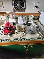 Overview of small kitchen appliances including food processors, mixers, and accessories on kitchen counter.