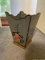 Angled view showing floral painted side with scalloped top and gold trim