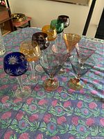 Front angle showing all 6 colorful goblets and 5 martini glasses on a floral tablecloth.
