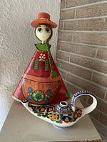 Decorative doll and ceramic pot displayed together, showing colorful traditional Argentine style.