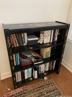 Full front view of wooden bookcase filled with books and a few small items showing overall structure and appearance.
