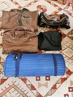 Wide shot of the lot showing four different bags and one blue rolled-up beach mat.