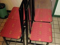 Top view of four black metal framed chairs with red seat upholstery.