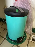 Front view of the turquoise trash can showing the closed black lid and step pedal.