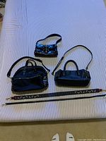 All three purses and two detachable straps laid flat on striped fabric background