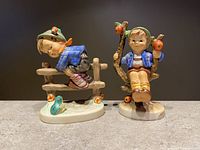 Both vintage Goebel Hummel figurines displayed side by side showing detailed colors and poses