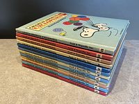 Stack of 12 vintage Charlie Brown's Cyclopedia volumes by Funk & Wagnalls, showing colorful spines and covers with Peanuts characters.