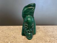 Front angled view of the polished green malachite tribal carved face with headdress showing detailed carving and banding patterns.