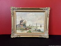 Front view of oil painting depicting Dutch windmill landscape, framed with ornate gold frame.