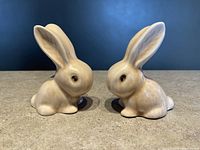 Pair of beige ceramic Sylvac bunny figurines with snub noses, viewed side by side from front