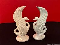 Front view of two ceramic swan vases placed side by side showing detailed wings and curved necks