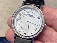 Close-up of watch face showing star and rhinestone design with STORM branding, silver-tone metal case.