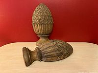 Two concrete pineapple corbels positioned on table, one standing and one lying sideways showing detailed pineapple texture and base