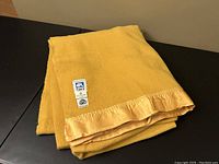 Folded yellow wool blanket with silky edges showing the Ayers label.