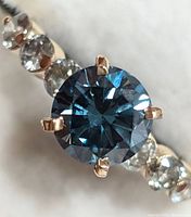 Close-up view of central blue moissanite and adjacent diamond accents from top angle