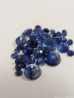 Cluster of loose rose-cut blue sapphires on white background showing various sizes and shapes.