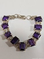 Top-down view of silver bracelet with eight rectangular amethyst stones and hook-and-loop clasp