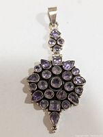 Front view of a large silver pendant with many amethyst stones in round, pear, and square cuts.