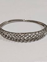Close-up front view of silver-tone bangle with CZ stones arranged in crisscross pattern