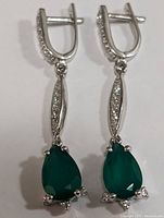 Front view of both earrings showing pear-shaped green onyx stones and cubic zirconia accents on silver metal.
