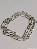 Photo shows 18-inch silver necklace coiled, highlighting chain links style and shine