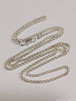 Full view of the silver chain necklace laid flat, displaying the chain style and length.